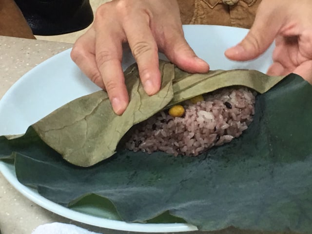 Nasi merah setengah matang dibungkus daun lotus. (Foto: dok: Aji Surya)