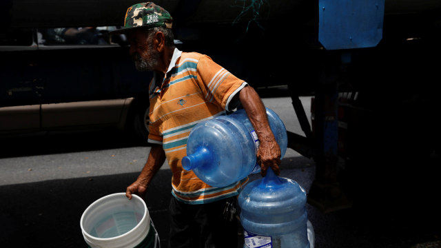 Pria di Puerto Rico menunggu giliran mengisi air (Foto: REUTERS/Carlos Garcia Rawlins)