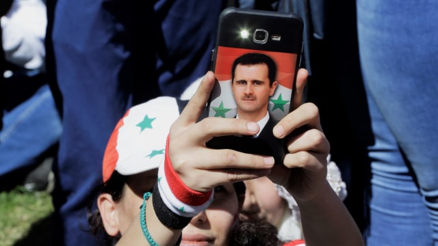 Foto Bashar al-Assad di ponsel suporter Suriah. (Foto: AFP/Louai Beshara)