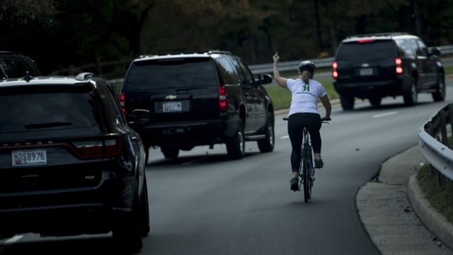 Pesepeda melewati iring-iringan mobil Trump (Foto: Brendan Smialowski / AFP)