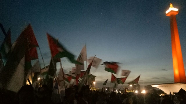 Peserta aksi mengibarkan bendera Palestina. (Foto: Adim Mugni/kumparan)