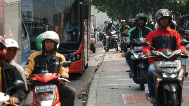Pengguna sepeda motor melintasi trotoar  (Foto: Jamal Ramadhan/kumparan)