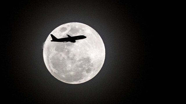 Sebuah pesawat melintasi bulan purnama (Foto: AFP PHOTO / NOEL CELIS)