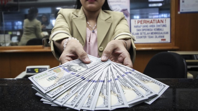 Petugas menunjukan uang dolar AS. (Foto: ANTARA FOTO/Dhemas Reviyanto)