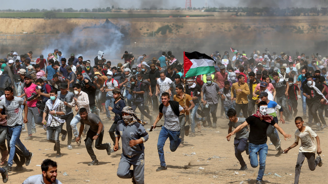 Warga Palestina menghindar dari gas air mata. (Foto: REUTERS / Ibraheem Abu Mustafa)