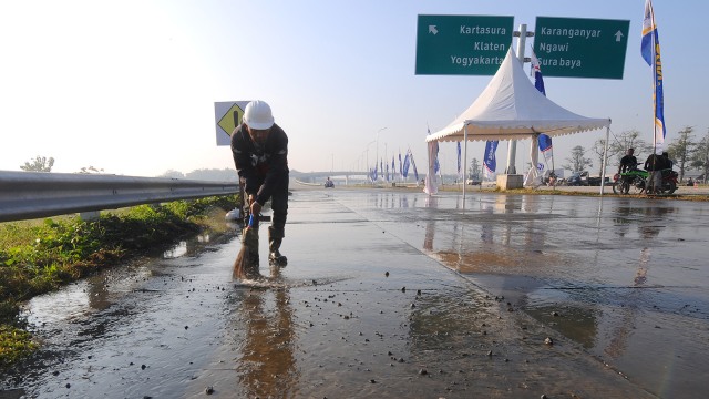 Pekerja bersihkan sisa material pembangunan tol. (Foto: ANTARA FOTO/Aloysius Jarot Nugroho)