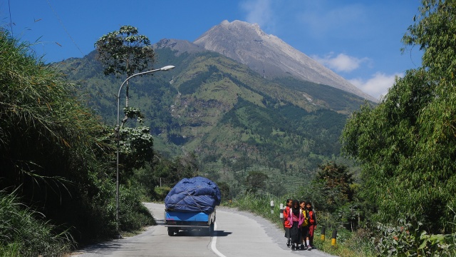 Warga lintasi jalan dengan latar gunung Merapi. (Foto: ANTARA FOTO/Aloysius Jarot Nugroho)