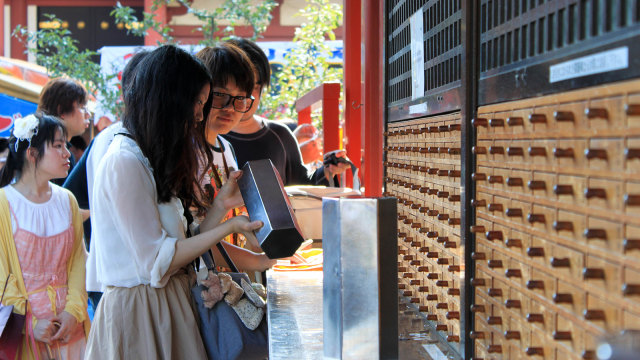 Wisatawan Sedang Mengocok Kotak Omikuji (Foto: Flickr / Yukino Kondo)