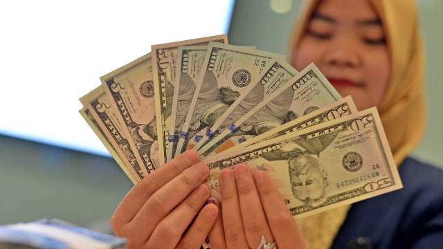 Petugas memperlihatkan pecahan uang dolar AS (Foto: ANTARA FOTO/Wahyu Putro)