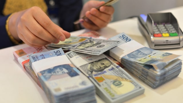 Petugas menghitung pecahan uang dolar AS (Foto: ANTARA FOTO/Wahyu Putro)