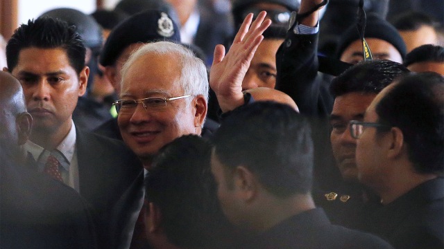 Mantan perdana menteri Malaysia, Najib Razak, melambai ketika dia berjalan ke ruang sidang di pengadilan di Kuala Lumpur. (Foto: REUTERS / Lai Seng Sin)