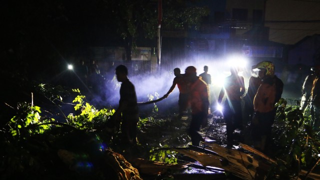 Petugas BPBD berusaha mengangkat batang pohon yang tumbang dampak angin puting beliung, di Jalan Ngumban Surbakti, Medan, Sumatera Utara. (Foto: Antara/Irsan Mulyadi)