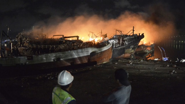 Sejumlah warga dan nelayan berusaha memadamkan api yang masih membakar sejumlah kapal ikan di Pelabuhan Benoa, Denpasar. (Foto: ANTARA FOTO/Fikri Yusuf)