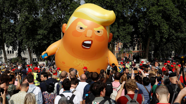 Penonton berdiri di depan balon udara yang menggambarkan Presiden AS Donald Trump, di Parliament Square. (Foto: REUTERS / Peter Nicholls)