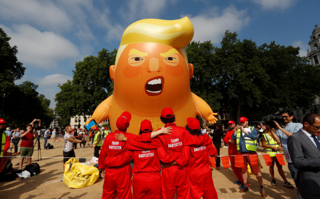 Demonstran berdiri di depan balon udara yang menggambarkan Presiden AS Donald Trump. (Foto: REUTERS/Peter Nicholls)