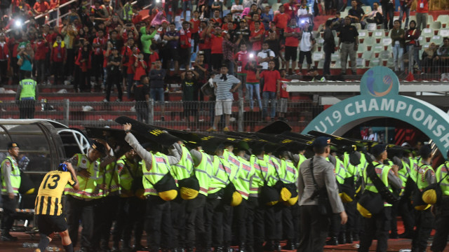 Petugas keamanan berusaha melindungi pesepak bola Malaysia U19 Mohamad Izzuddin (kiri) dari lemparan suporter Indonesia usai laga semi final Piala AFF U19 di Gelora Delta Sidoarjo, Sidoarjo, Jawa Timur, Kamis (12/7). (Foto:  ANTARA FOTO/Zabur Karuru)