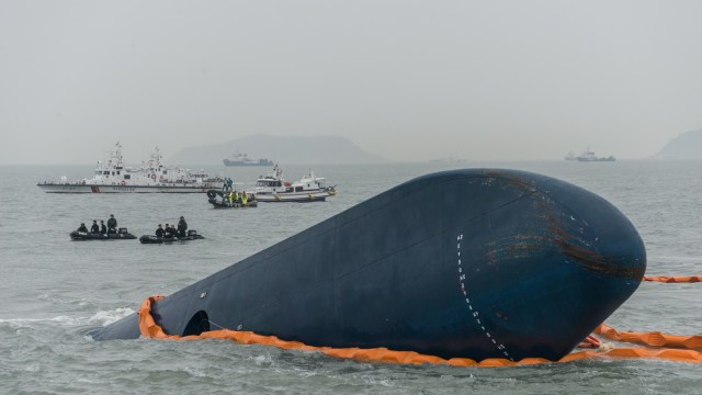 Penjaga pantai dan kapal penyelamat mengitari lambung kapal Sewol yang terbalik 24 jam setelah tenggelam, di lepas pantai pulau Jindo selatan selatan Korea Selatan. (Foto: AFP/ Ed Jones)