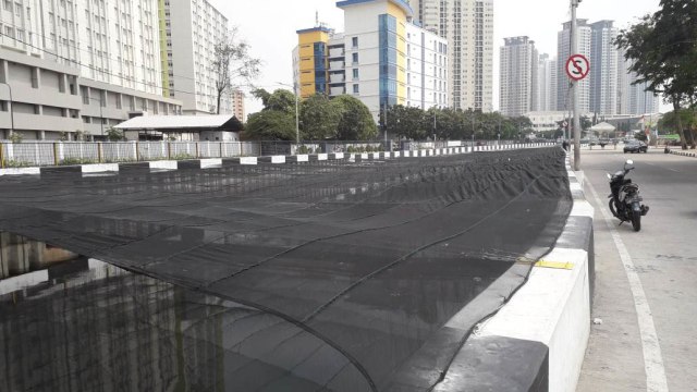 Kali Item di sekitar Wisma Atlet Kemayoran ditutupi jaring tipis untuk menutupi bau dan warna hitam airnya (Foto: Istimewa)