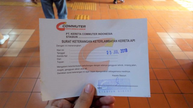 Petugas stasiun membagikan surat keterangan keterlambatan kereta api untuk karyawan yang terlambat masuk kerja. (Foto: Nadia Riso/kumparan)