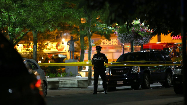 Seorang petugas polisi berjaga-jaga di lokasi penembakan di Toronto, Kanada, Minggu (22/7). (Foto: Reuters/Chris Helgren)