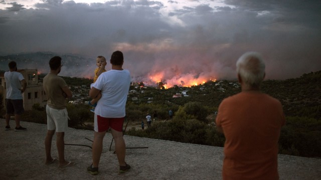 Saat warga melihat kebakaran hutan yang mulai masuk pemukiman Rafina, Athena, Yunani. (Foto: AFP/Angelos Tzortzinis)