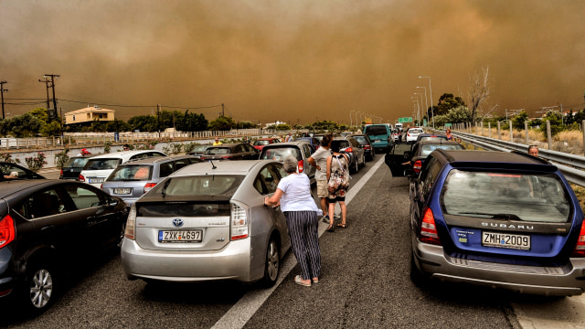 Mobil warga terblokir di jalan nasional dekat dengan area Athena, Yunani, akibat kebakaran hutan yang melanda. (Foto: AFP/Valerie Gache)