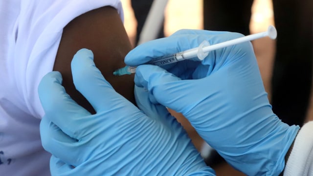 Seorang pekerja Organisasi Kesehatan Dunia (WHO) memberikan vaksinasi. Foto: Reuters/Kenny Katombe