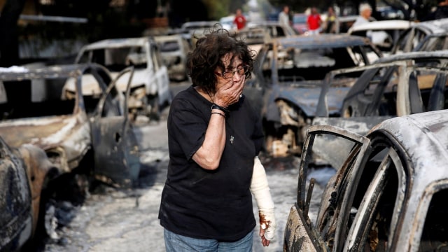 Reaksi salah satu warga ketika ia mencoba untuk mencari anjingnya setelah kebakaran yang terjadi di Desa Mati, Yunani. (Foto: REUTERS/Costas Baltas)