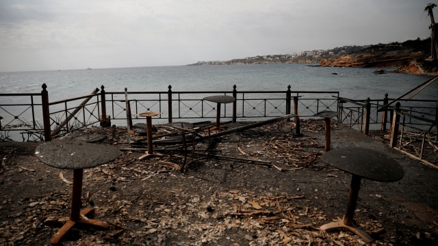 Meja dan kursi di sebuah kafe ikut terbakar di Desa Mati, Yunani. (Foto: REUTERS/Alkis Konstantinidis)