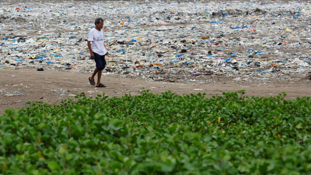 Seorang pria berjalan di Pantai Muambai yang penuh dengan sampah. (Foto: REUTERS/Francis Mascarenhas)