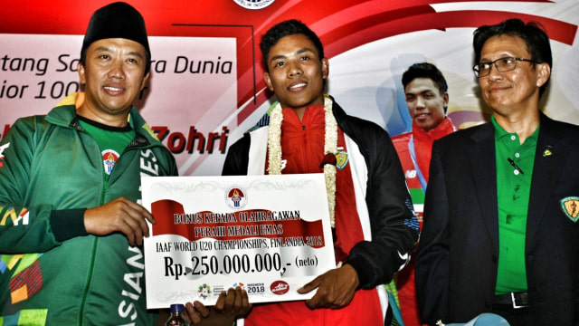 Menpora Imam Nahrawi (kiri) disaksikan Sekjen PB PASI Tigor Tanjung (kanan) memberikan penghargaan kepada Atlet Indonesia juara dunia atletik nomor Lari 100 meter U-20 Lalu Muhammad Zohri. (Foto: ANTARA FOTO/Muhammad Iqbal)
