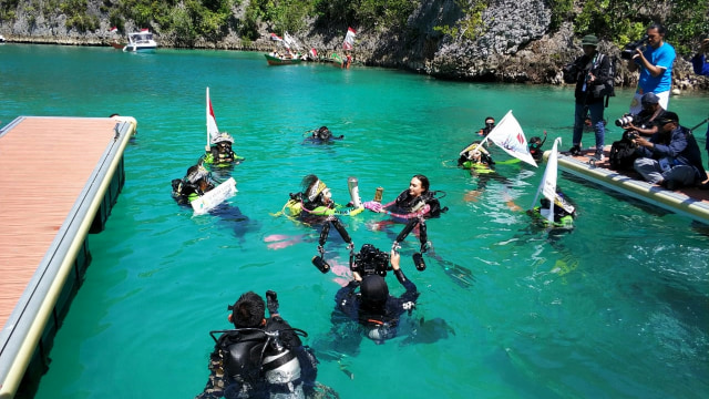 Replika obor Asian Games 2018  dibawa menyelam oleh Ny Tri Tito Karnavian didampingi Nadine Chandrawinata, bersama penyelam lainnya di Hidden Bay. Piaynemo, Raja Ampat,  (Foto: Dok. Humas Polri)