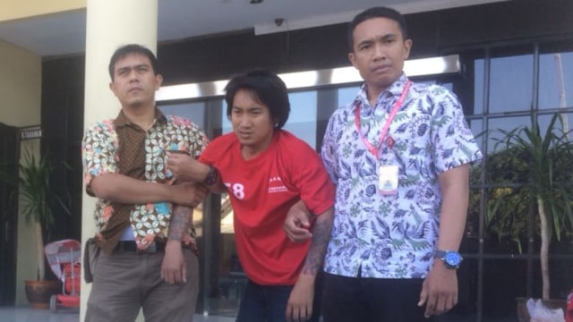 Polisi membawa Erik (tengah), begal kambuhan yang berhasil di tangkap di Surabaya. (Foto: Phaksy Sukowati/kumparan)