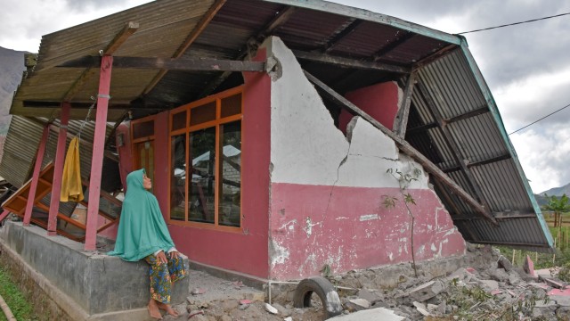 Warga berada di rumahnya yang rubuh akibat gempa di Desa Sembalun Bumbung, Kecamatan Sembalun, Selong, Lombok Timur, NTB, Minggu (29/7).  (Foto: Antara/Ahmad Subaidi)