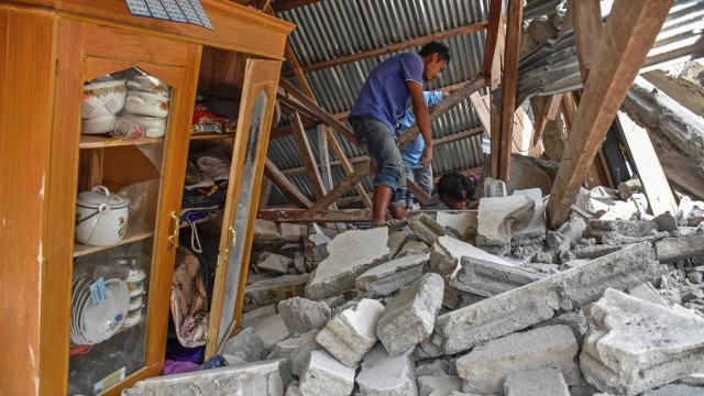 Warga mencari perlengkapan wisatawan asal Malaysia yang tewas tertimpa rumah roboh akibat gempa, di Desa Sajang, Kecamatan Sembalun, Selong, Lombok Timur, NTB, Minggu (29/7). (Foto: Antara/Ahmad Subaidi)