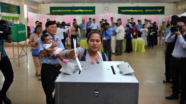 Seorang pemilih memasukan surat suara ke dalam kotak selama pemilihan umum di Phnom Penh, Minggu (29/7). (Foto: AFP PHOTO / Manan Vatsyayana)