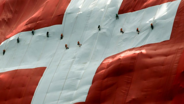 Pengibaran bendera Swiss berukuran raksasa di Mount Saentis, Swiss, Selasa (31/7). Foto: Reuters/Arnd Wiegmann