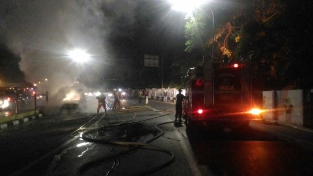 Petugas memadamkan sebuah mobil yang terbakar di Jl Raya Pondok Gede. (Foto: Twitter/@TMCPoldaMetro)