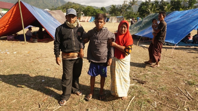 Orang tua membantu  anaknya berjalan di tempat pengungsian korban gempa Desa Menggala, Kab. Lombok Utara, NTB, Senin (6/8). (Foto: Jamal Ramadhan/kumparan)
