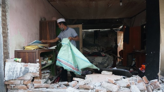 Elmi (56) memilah barang-barang yang tersisa pasca gempa di rumahnya di Desa Karang Pangsor, Kec. Pemenang, Kab. Lombok Utara, Selasa (7/8). (Foto: Jamal Ramadhan/kumparan)