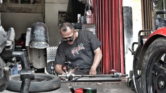 Catur Bambang (45) Pendiri Bengkel untuk Difabel, saat memodifikasi motor roda tiga di kawasan Rempoa, Ciputat, Tangerang Selatan, Kamis (9/8/2018). (Foto: Tomy Wahyu Utomo/kumparan)