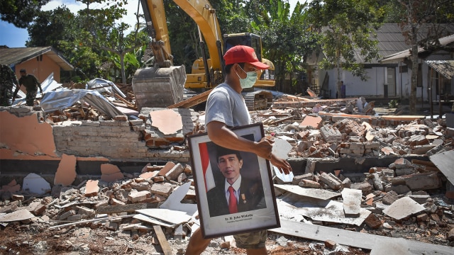 Warga memindahkan poster Presiden Joko Widodo dari bangunan SDN 2 Kekait yang rusak akibat gempa di Gunungsari, Lombok Barat, NTB, Minggu (12/8/2018). (Foto: ANTARA FOTO/Ahmad Subaidi)