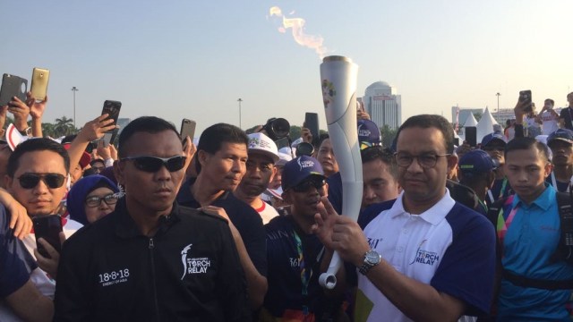 Gubernur Anies Baswedan membawa obor Asian Games 2018 di Monas, Sabtu (18/82018). (Foto: Moh Fajri/kumparan)