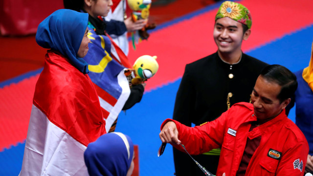 Jokowi menyerahkan medali emas taekwondo pada Defia Rosmaniar. (Foto: Reuters/Cathal Mcnaughton)