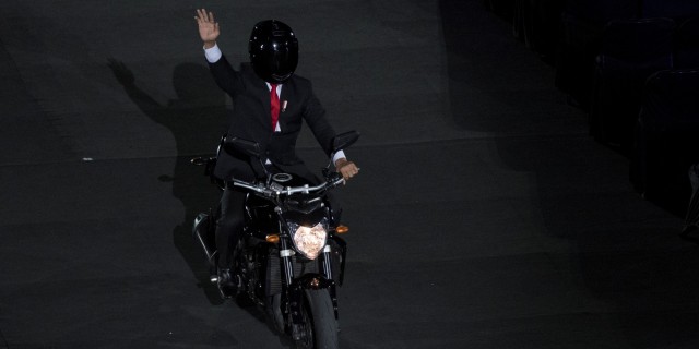 Presiden Joko Widodo mengendarai motor sambil melambaikan tangan saat pembukaan Asian Games ke-18 tahun 2018 di Stadion Utama Gelora Bung Karno, Jakarta, Sabtu (18/8). (Foto: INASGOC/Rosa Panggabean)