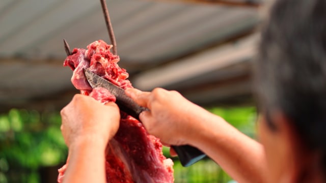 Ilustrasi Pria Memotong Daging Kurban (Foto: Shutterstock)