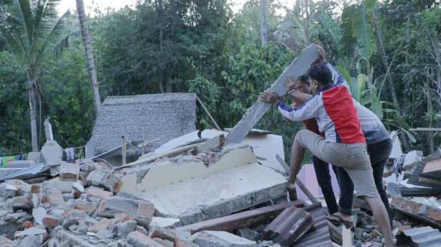 Warga Lombok Utara membersihkan reruntuhan bangunan. (Foto: Dwi Herlambang/kumparan)