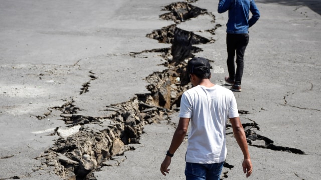 Sejumlah orang melintas di areal parkir ruang tunggu yang retak akibat gempa, di Pelabuhan Kayangan, Lombok Timur, NTB, Senin (20/8).  (Foto: Antara/Ahmad Subaidi)