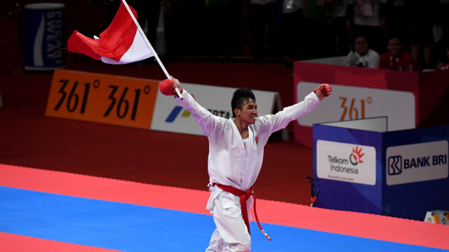 Atlet karate putra, Rifki Ardiansyah Arrosyiid, melakukan selebrasi dengan membawa bendera Indonesia usai memenangi nomor kumite 60 kg. (Foto: Antara/Ginanjar)