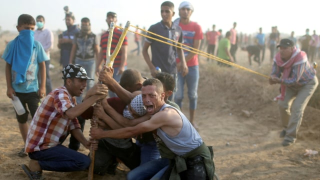 Bentrokan warga Palestina dan tentara Israel di pagar perbatasan antara Israel dan Gaza. (Foto: Reuters/Ibraheem Abu Mustafa)